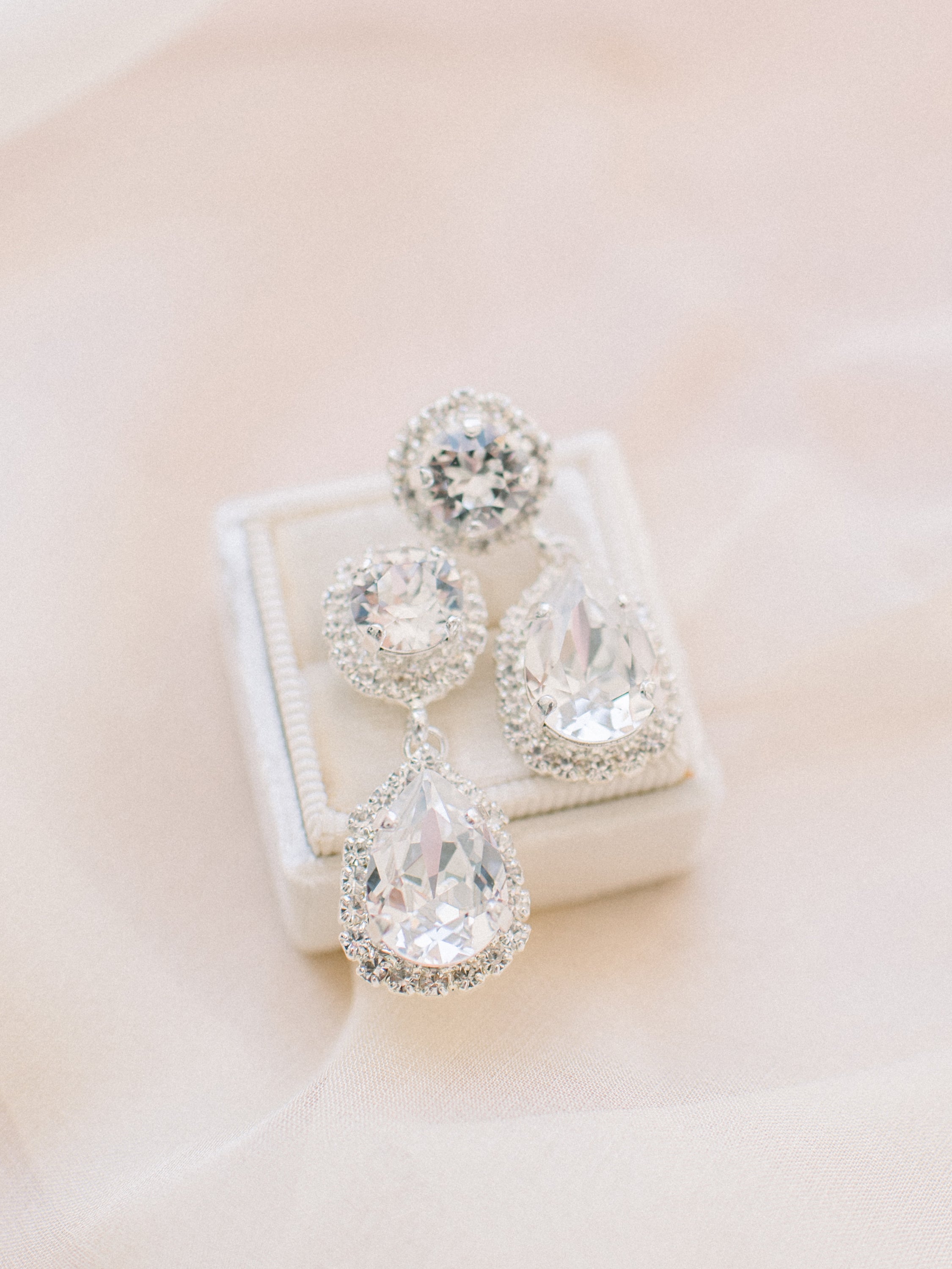 A pair of elegant teardrop crystal earrings with intricate halo detailing, perfect for a bride's wedding day look.