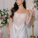 Woman in a white wedding dress standing in a decorated room with flowers and candles wearing Sarah Gauci Jewelry