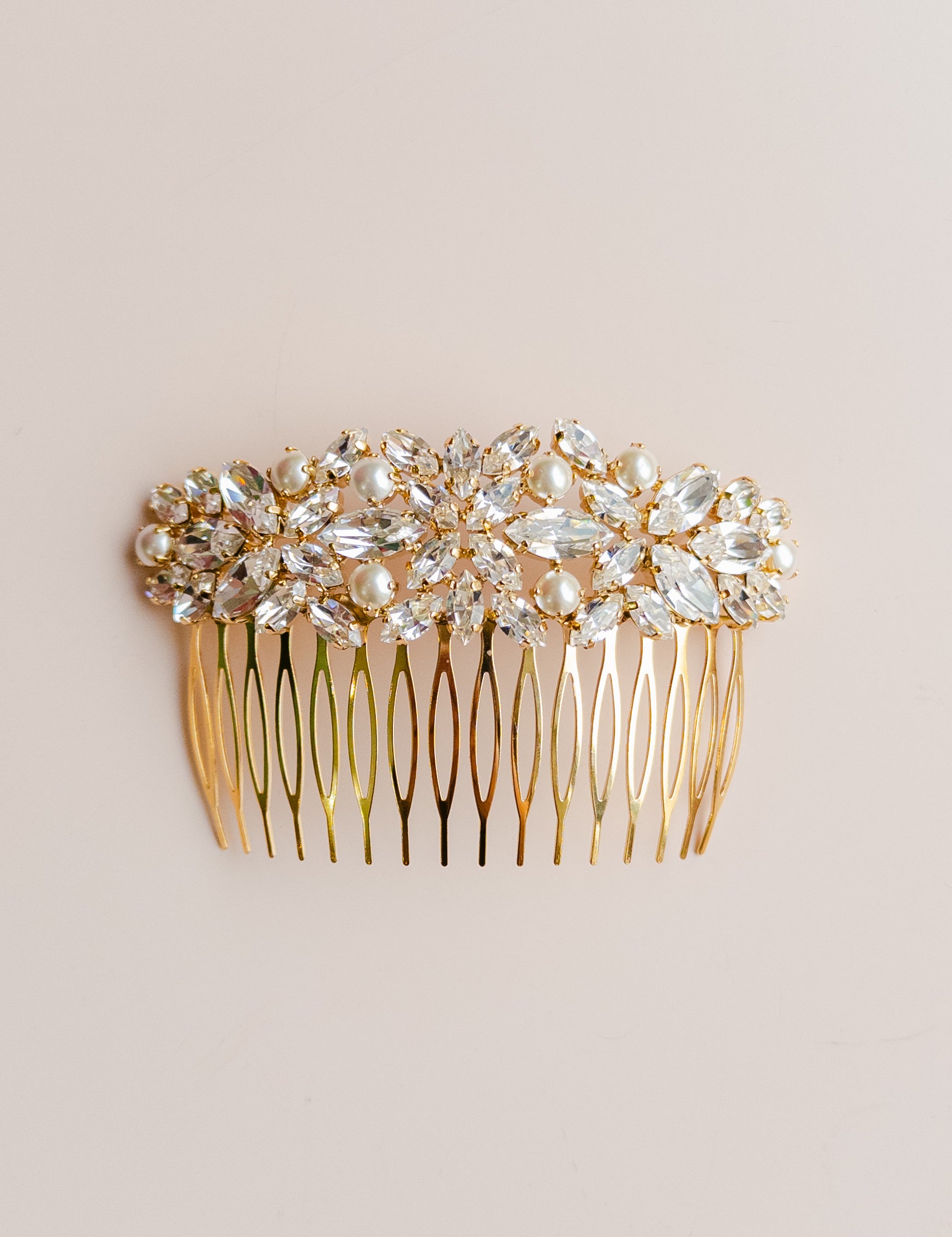 Gold hair comb with crystal embellishments on a beige background
