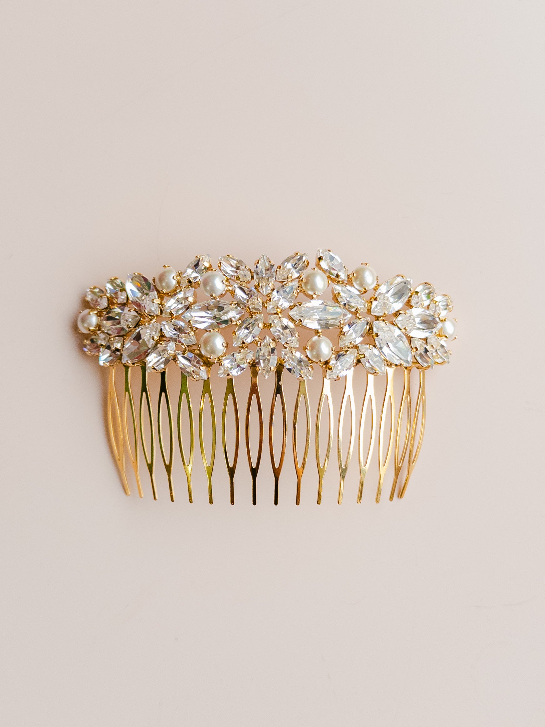 Gold hair comb with crystal embellishments on a beige background