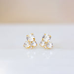 A pair of gold-plated brass stud earrings with clear crystals on a white background.