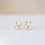 A pair of gold-plated brass stud earrings with clear crystals on a white background.