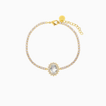 A gold-plated bracelet featuring a central oval crystal surrounded by smaller shimmering crystals, with a extender chain.