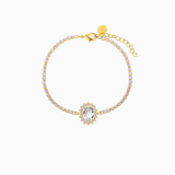 A gold-plated bracelet featuring a central oval crystal surrounded by smaller shimmering crystals, with a extender chain.