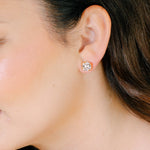Close-up of a person wearing a diamond stud earring.