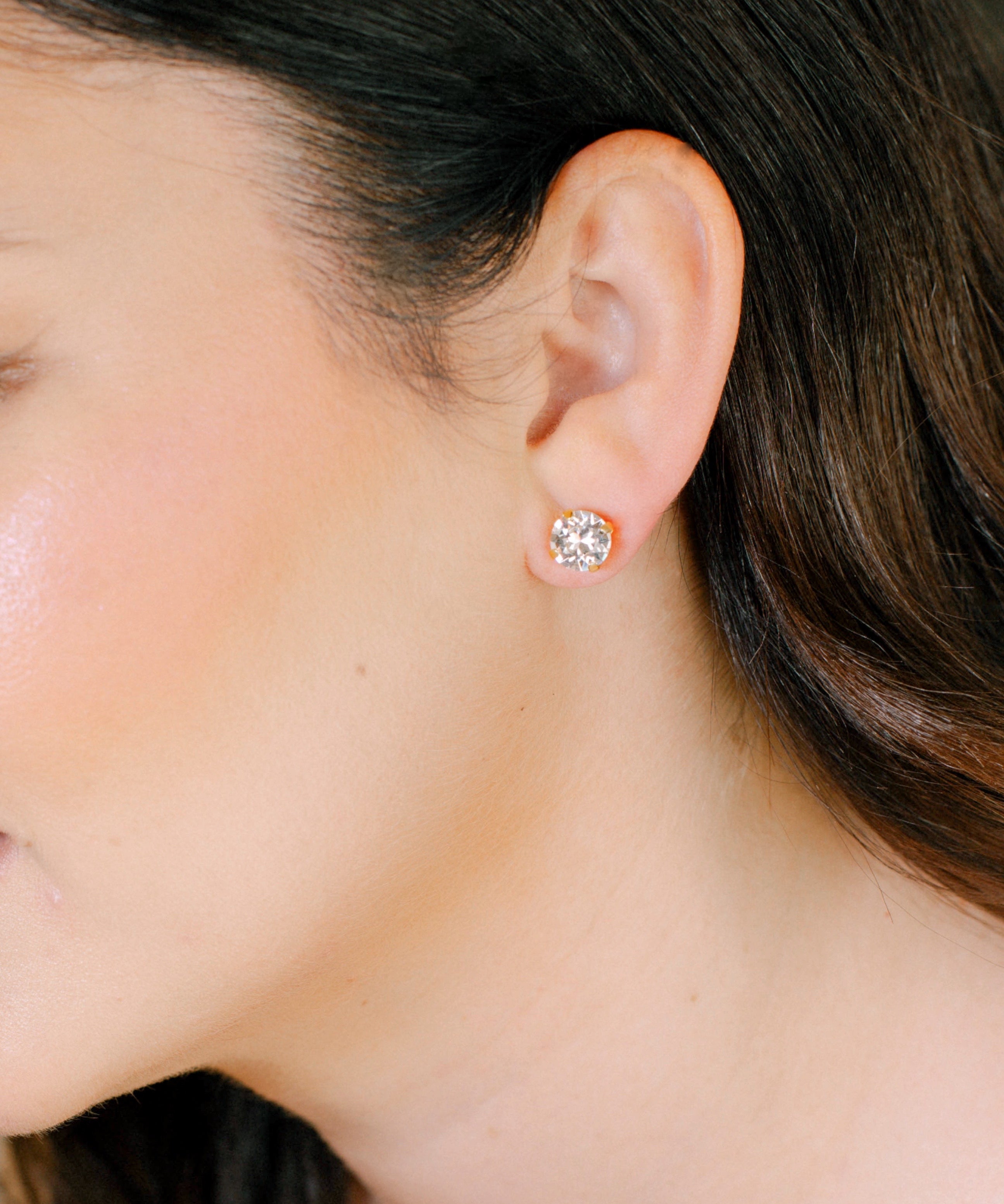 Close-up of a person wearing a diamond stud earring.