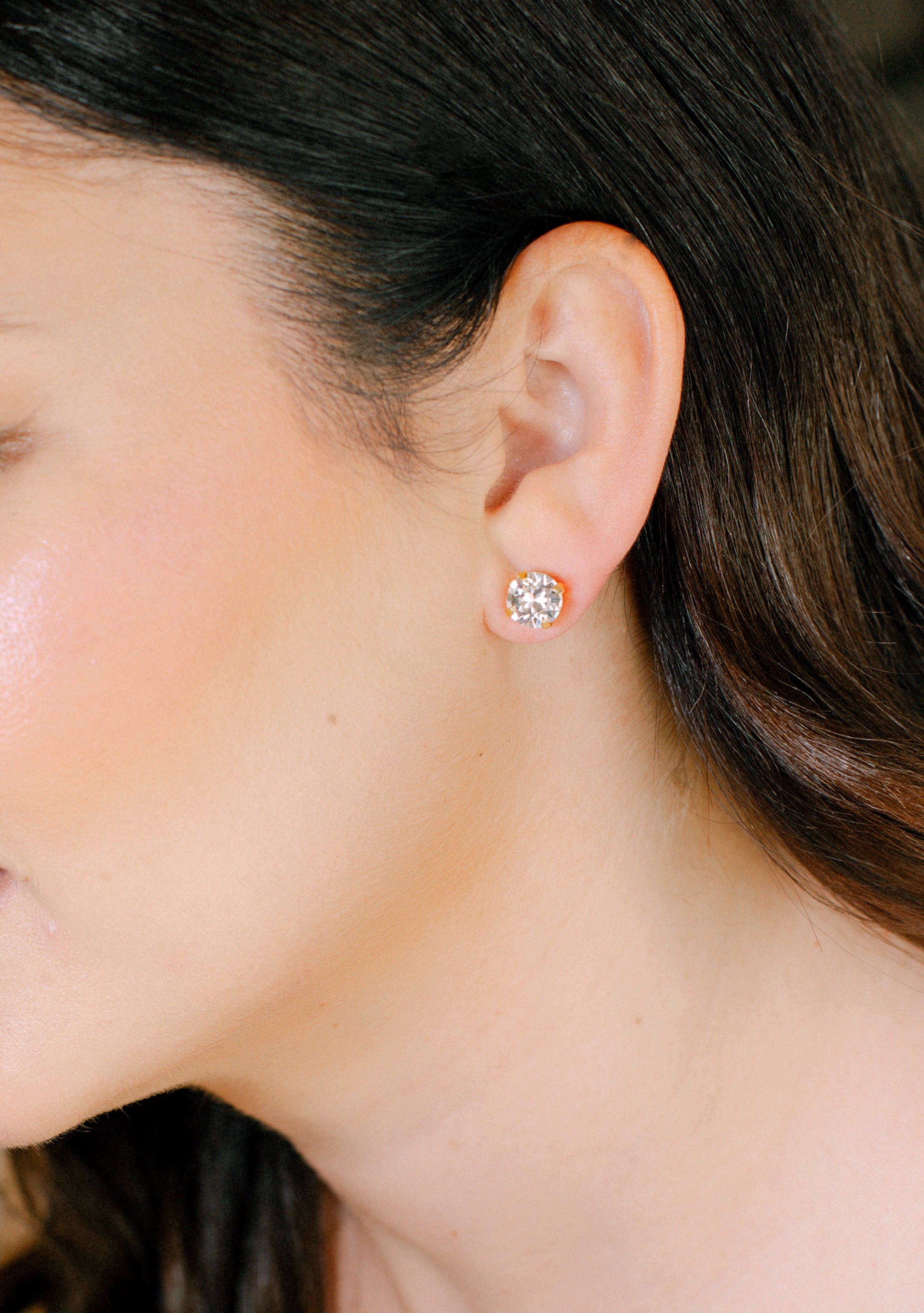 Close-up of a person wearing a diamond stud earring.