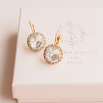 Gold earrings with clear gemstones on a pink box by Sarah Gauci Jewelry Malta 