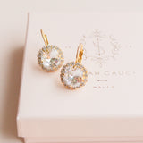 Gold earrings with clear gemstones on a pink box by Sarah Gauci Jewelry Malta 