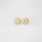 A pair of gold-colored stud earrings adorned with crystals, displayed against a white background.