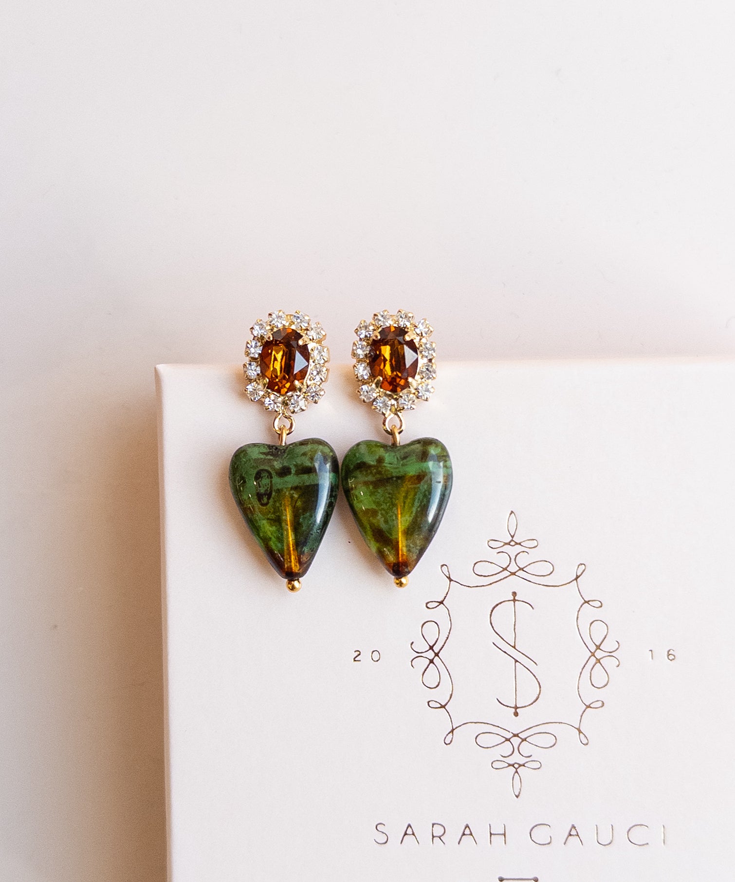 Heart-shaped earrings with green and brown stones by Sarah Gauci