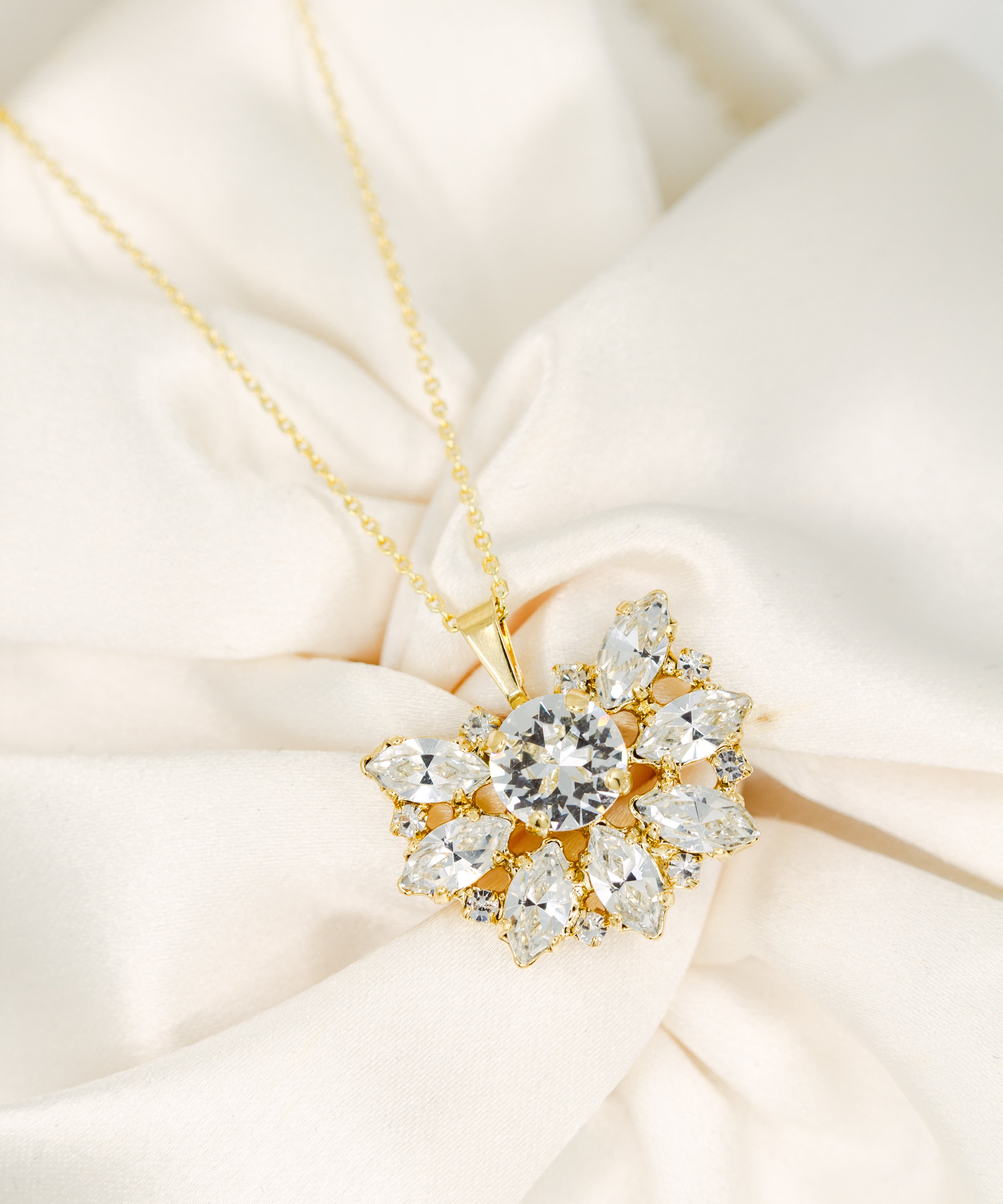 Gold necklace with a diamond pendant on a soft beige fabric background