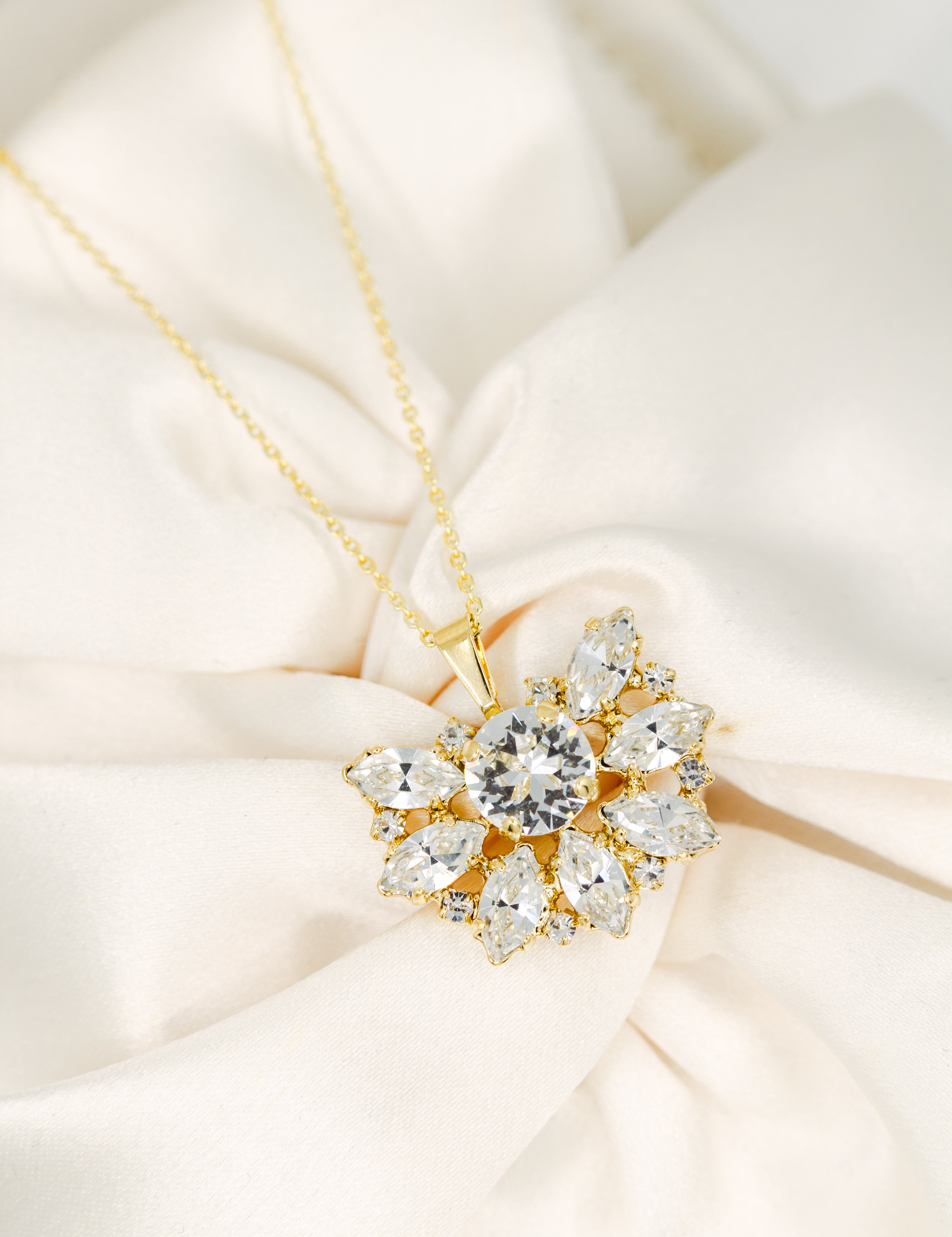 Gold necklace with a diamond pendant on a soft beige fabric background