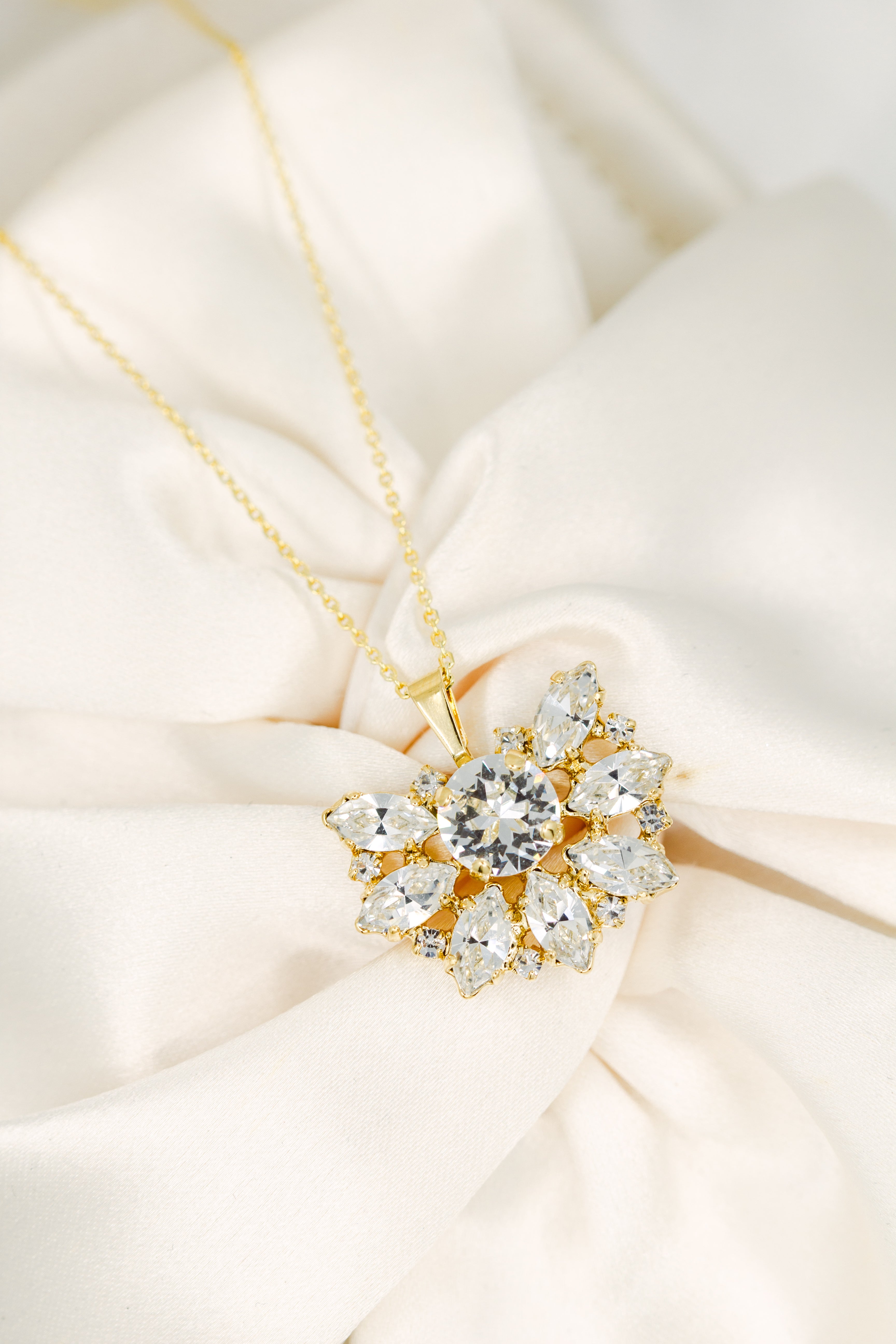 Gold necklace with a diamond pendant on a soft beige fabric background