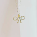 Gold bow-shaped pendant necklace on a light background