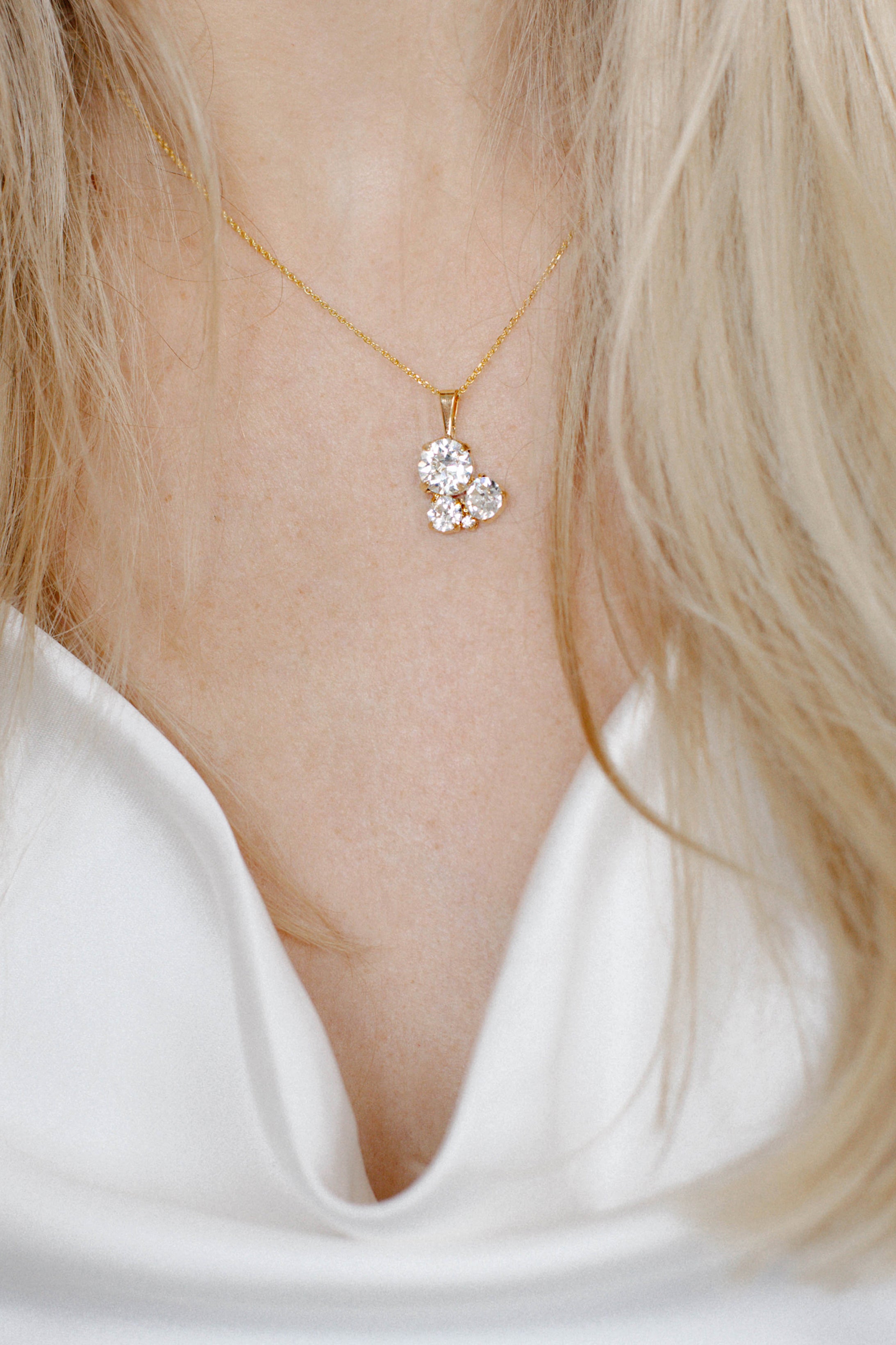 A gold-plated brass pendant necklace with a chain, featuring a floral-shaped crystal centerpiece.