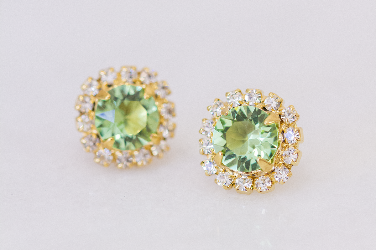 grand cassiopeia earrings in gold with surrounding halo of crystals and a peridot center crystal