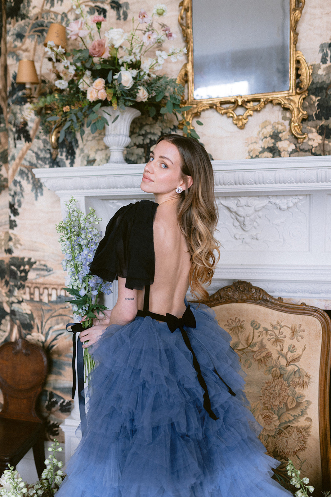 Woman in a wedding dress holding flowers next to a necklace with a ring box on a white background