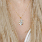 Gold necklace with a pendant worn by a person with blonde hair.