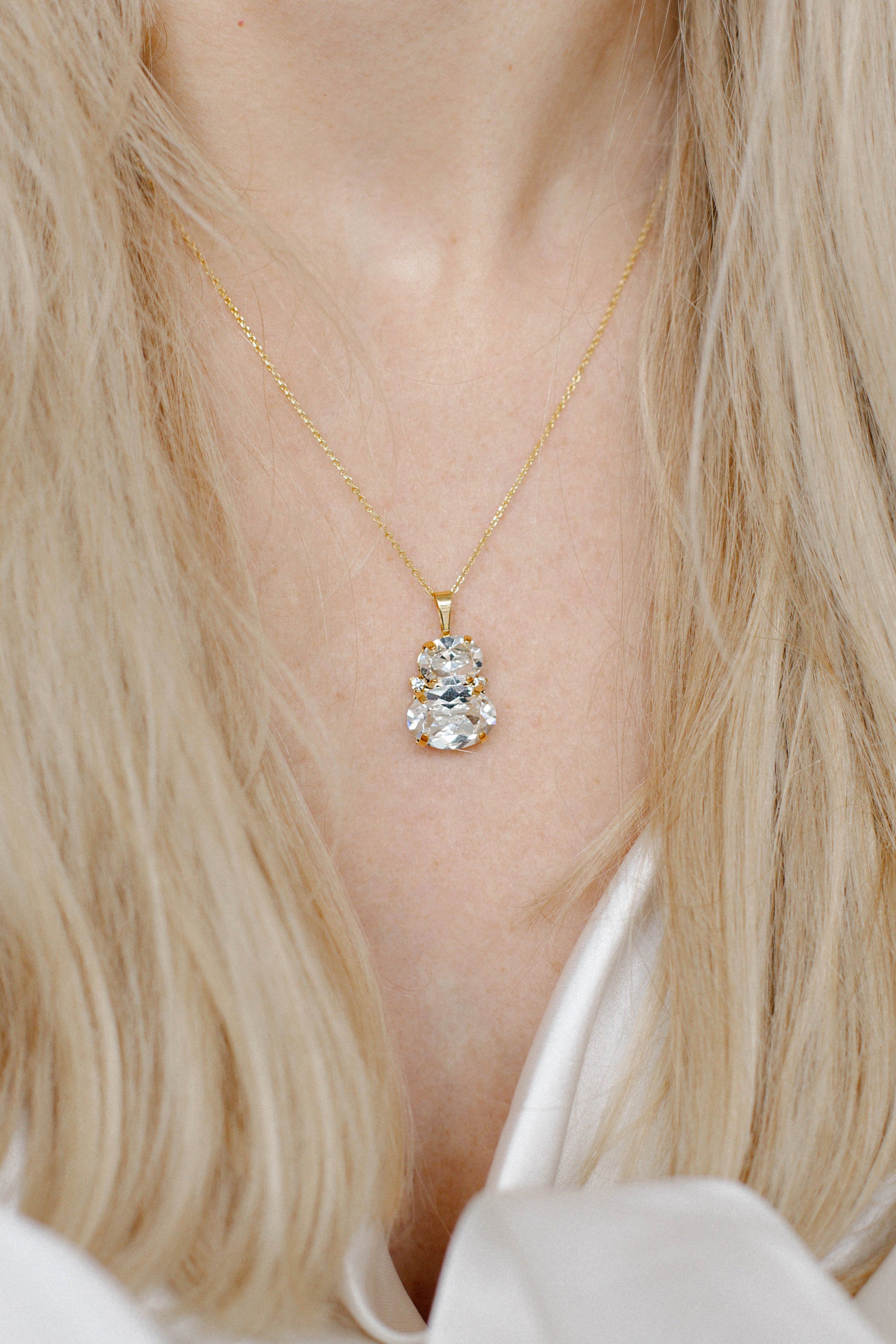 Gold necklace with a pendant worn by a person with blonde hair.