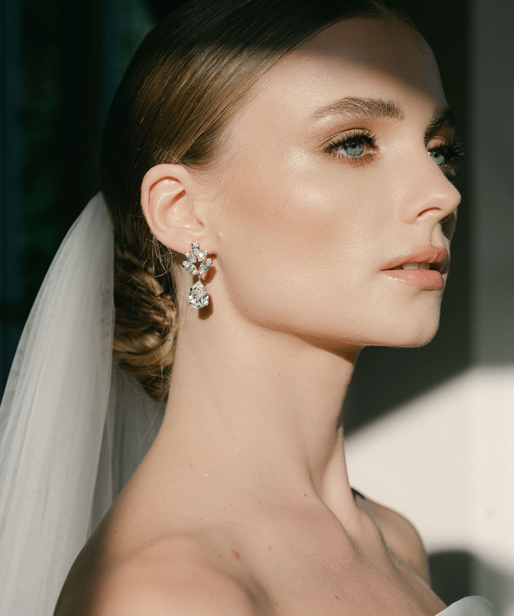 A woman wearing a white bridal veil and crystal stud drop earrings with a floral design by Sarah Gauci