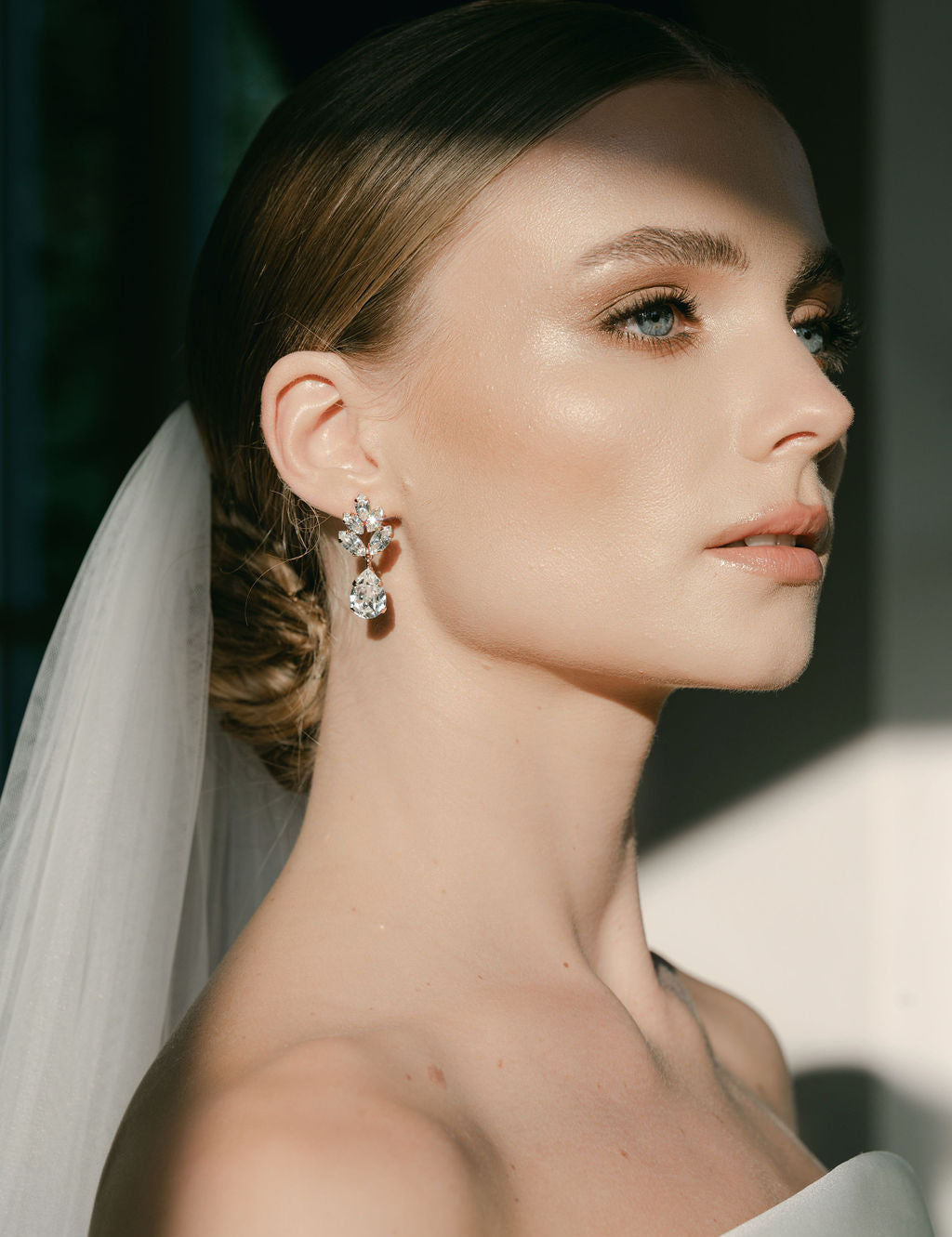 A woman wearing a white bridal veil and crystal stud drop earrings with a floral design by Sarah Gauci