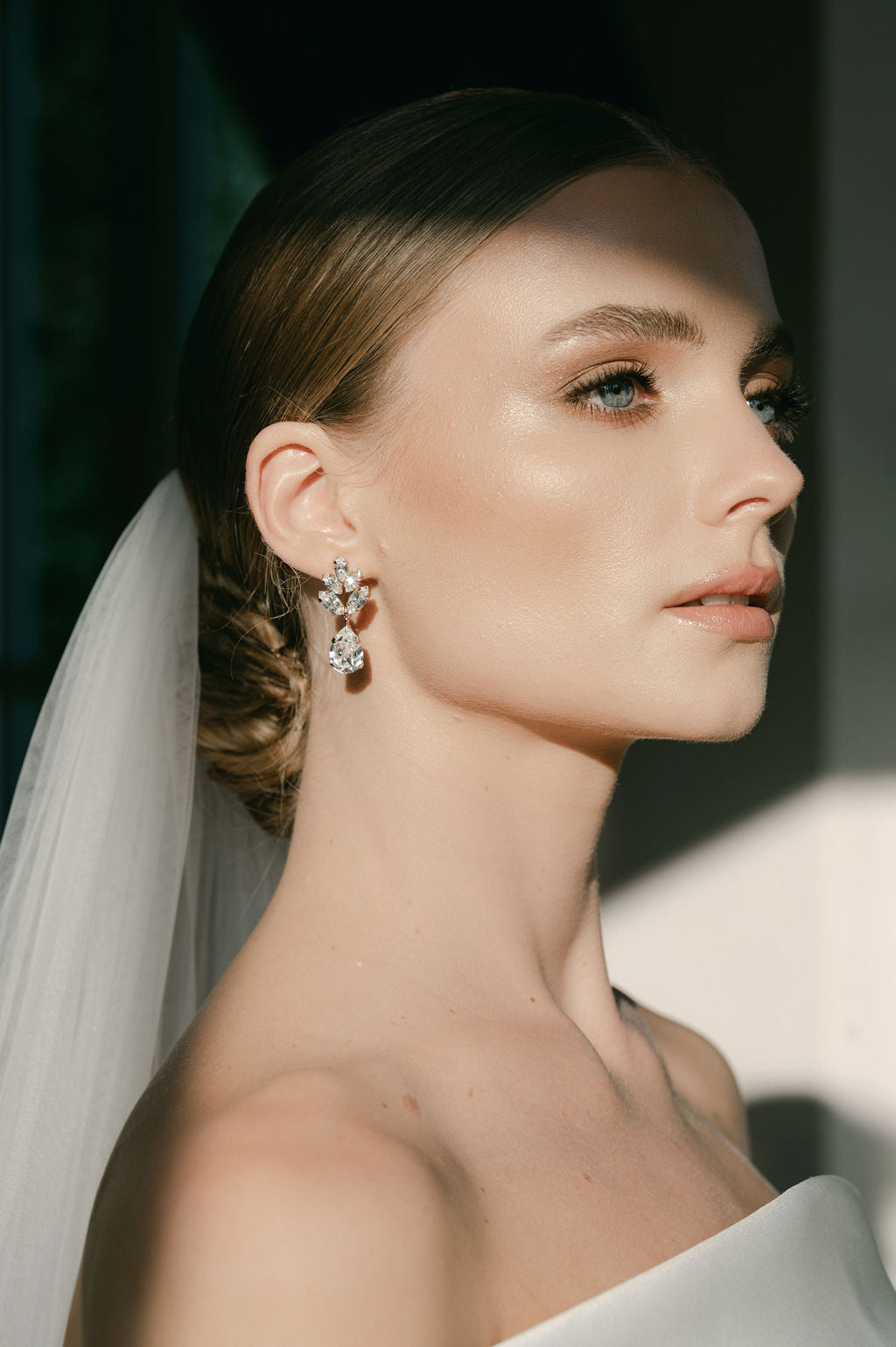 A woman wearing a white bridal veil and crystal stud drop earrings with a floral design by Sarah Gauci