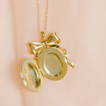 Gold locket with a bow on a pink background
