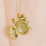 Gold locket with a bow on a pink background
