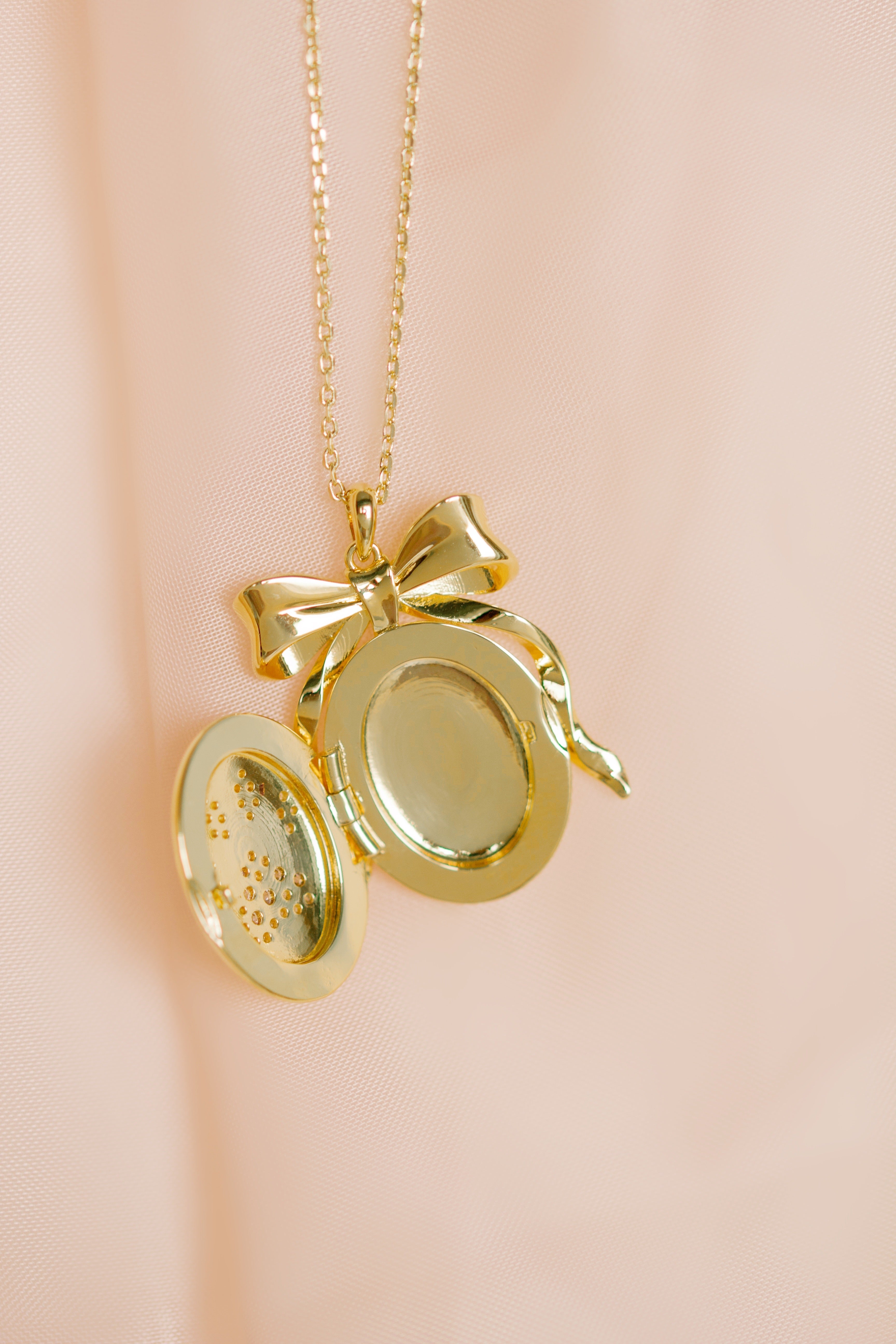 Gold locket with a bow on a pink background