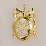 Gold pendant with paw print design on a beige background by Sarah Gauci Jewelry
