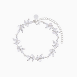 A rhodium-plated bracelet adorned with high-quality shimmering crystals and pearls, featuring a floral pattern and a chain extender.