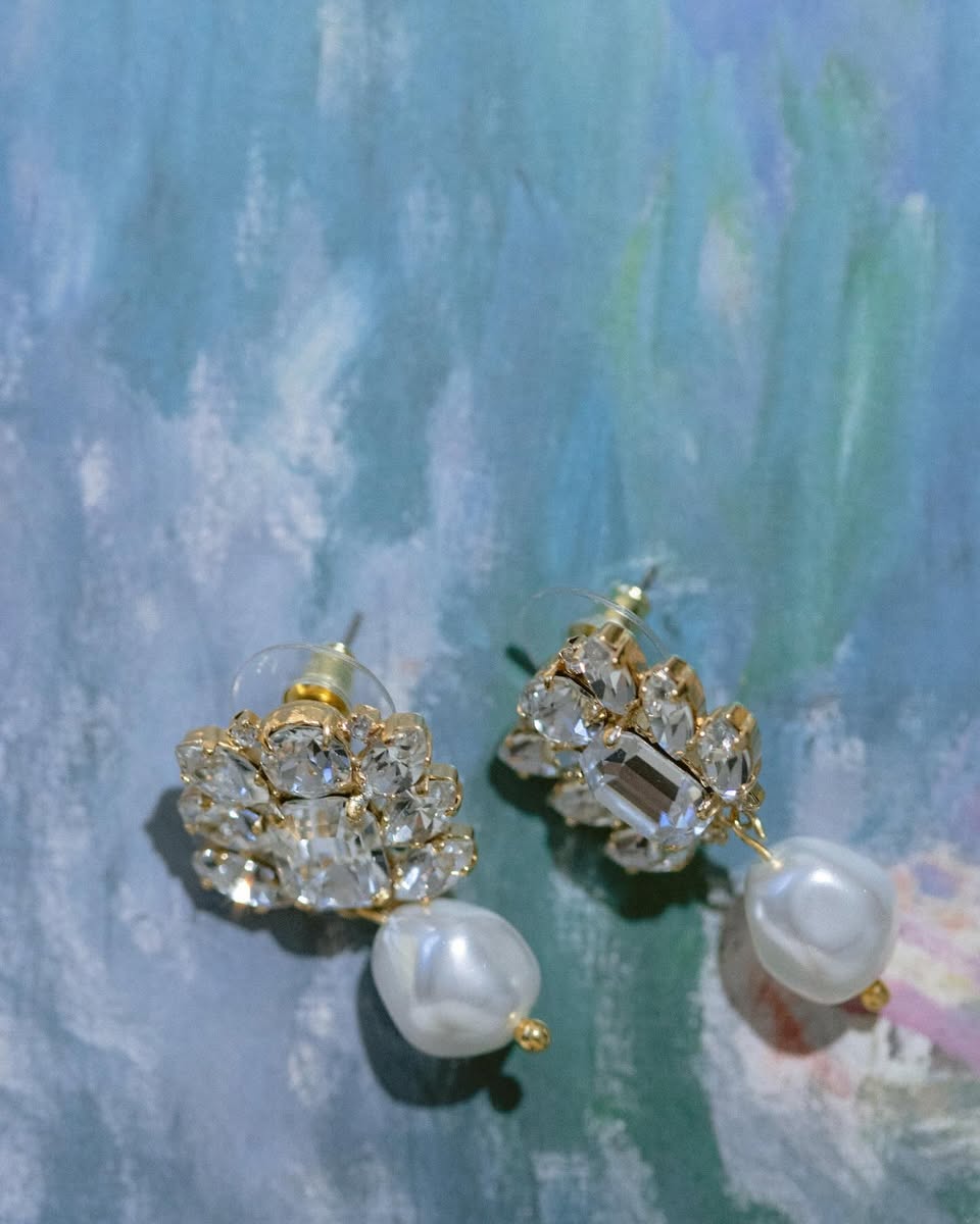 A pair of gold-plated pearl and crystal wedding earrings featuring a cluster of crystals and a baroque pearl drop by Sarah Gauci