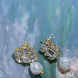 A pair of gold-plated pearl and crystal wedding earrings featuring a cluster of crystals and a baroque pearl drop by Sarah Gauci