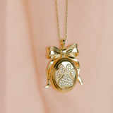 Gold necklace with a paw print locket on a pink background