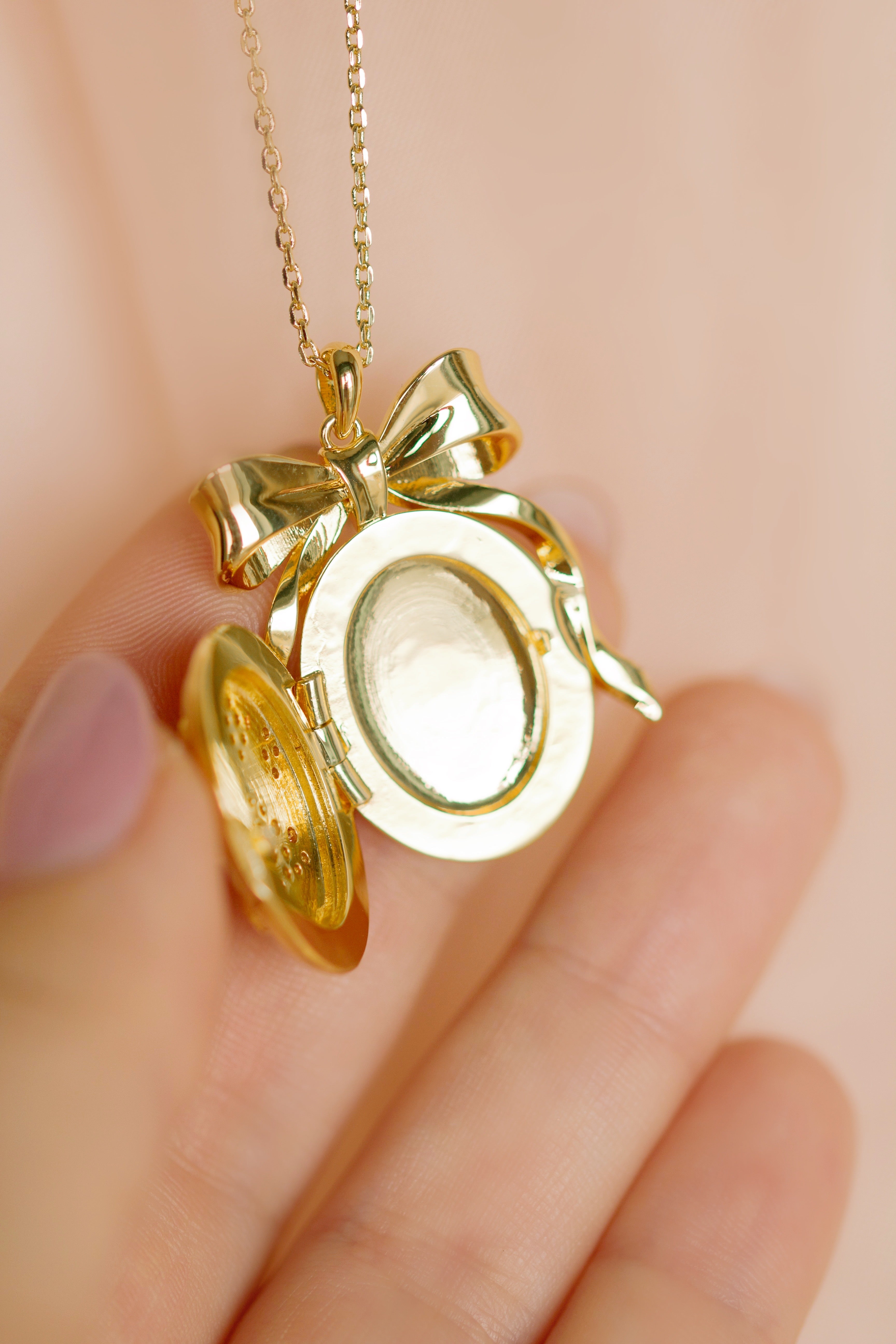Gold bow-shaped locket on a chain by Sarah Gauci Jewelry Malta