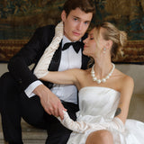 Man in tuxedo and woman in white dress sitting together in an elegant wedding setting