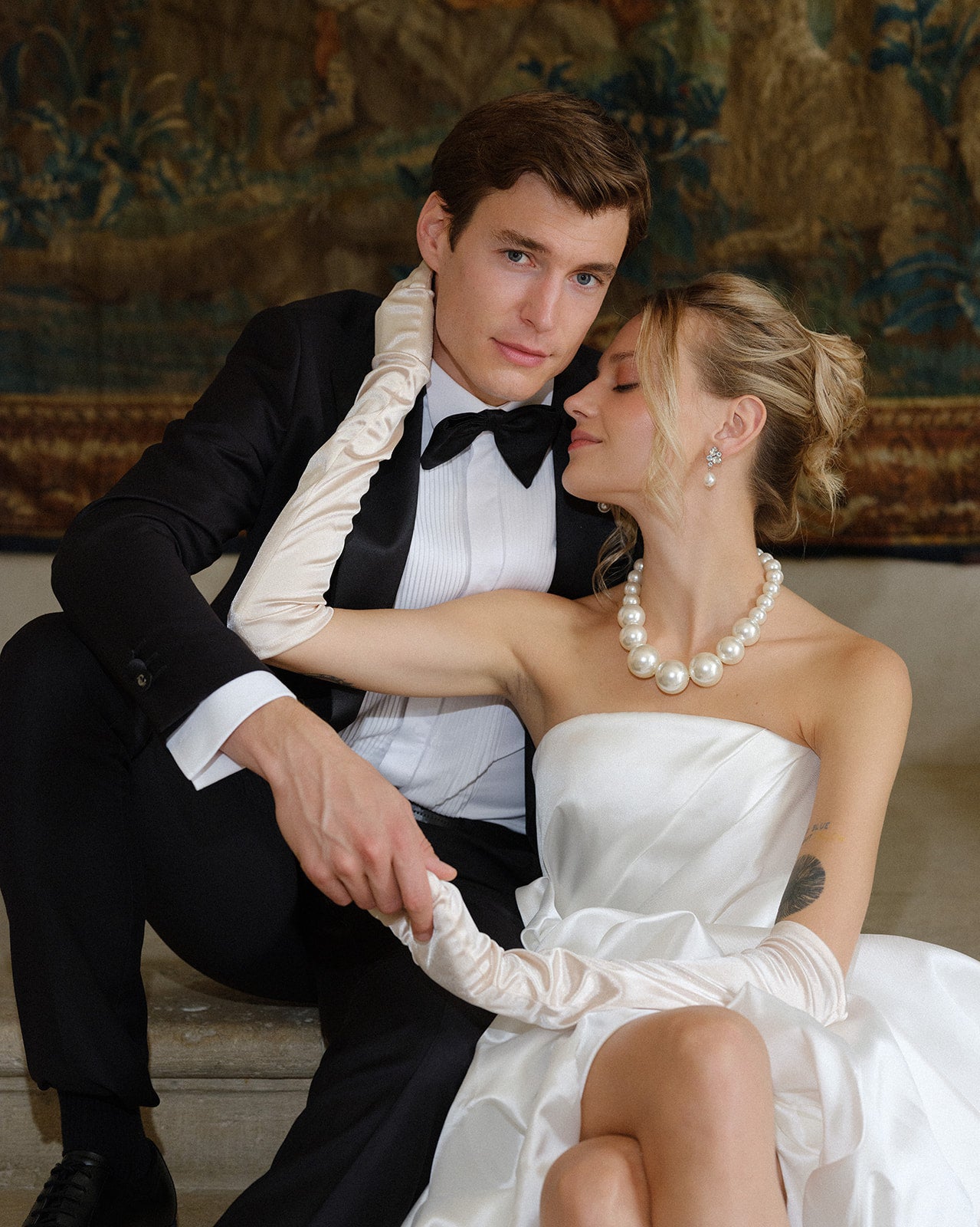 Man in tuxedo and woman in white dress sitting together in an elegant wedding setting