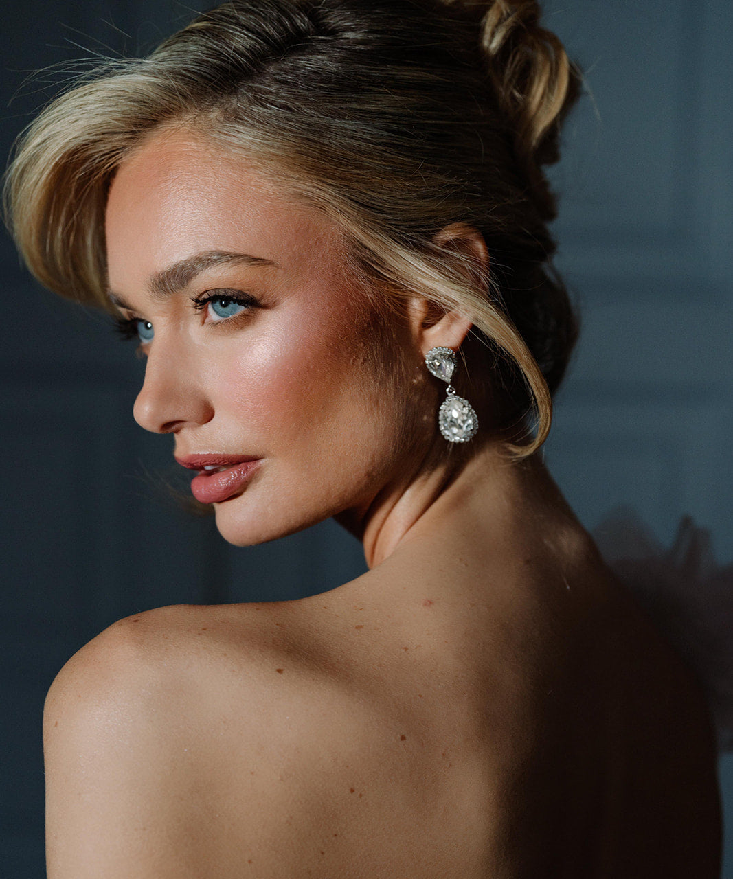 A woman viewed from the back wearing the Philippa Earrings, which are gold-plated with crystals, providing a glamorous and elegant look.