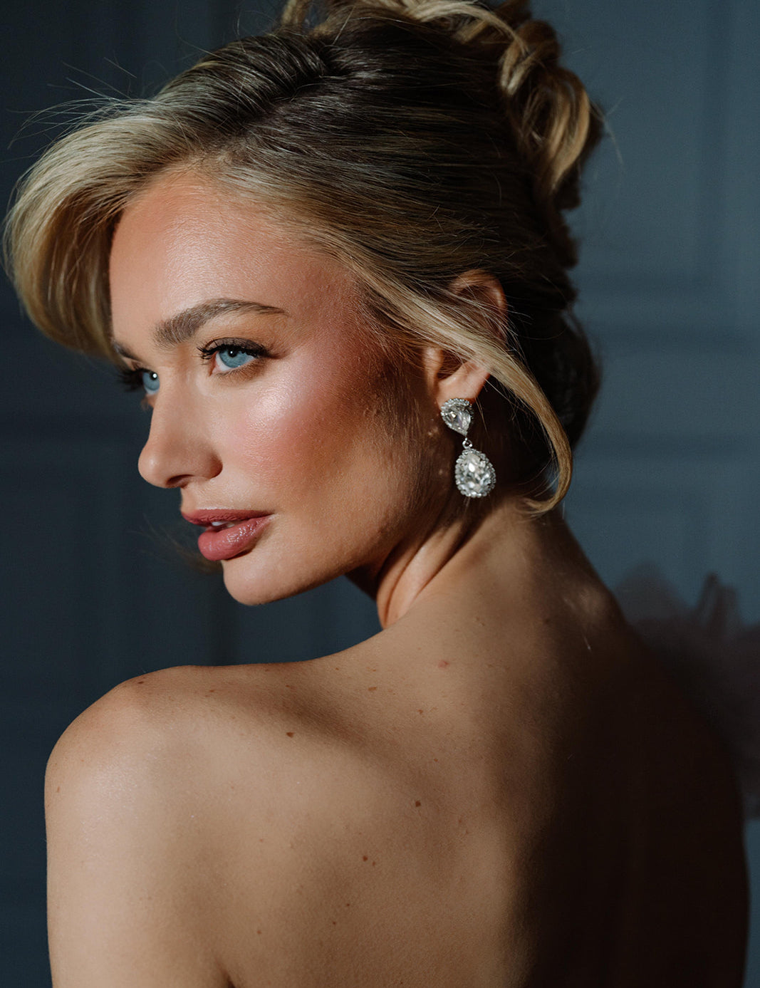 A woman viewed from the back wearing the Philippa Earrings, which are gold-plated with crystals, providing a glamorous and elegant look.