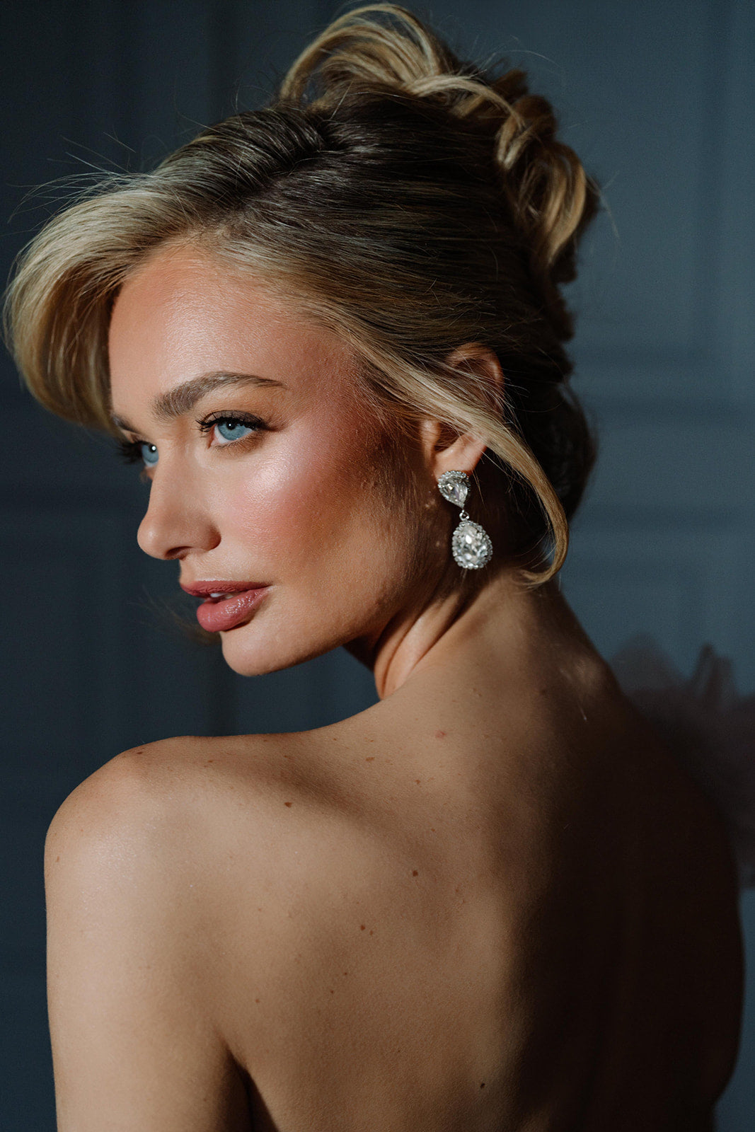 A woman viewed from the back wearing the Philippa Earrings, which are gold-plated with crystals, providing a glamorous and elegant look.