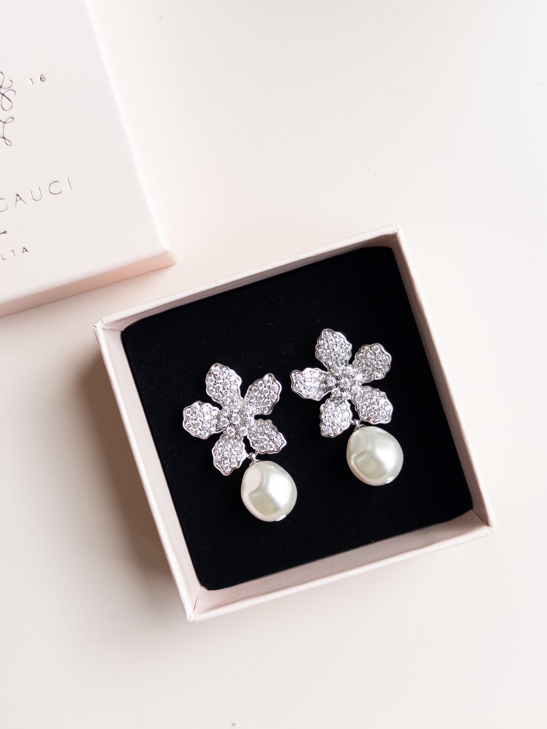 A pair of floral design pearl bridal earrings with a silver finish and white pearl drops, by Sarah Gauci