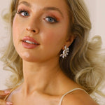 A woman wearing The Blanche Earrings, which are stud earrings with a clear crystal design.
