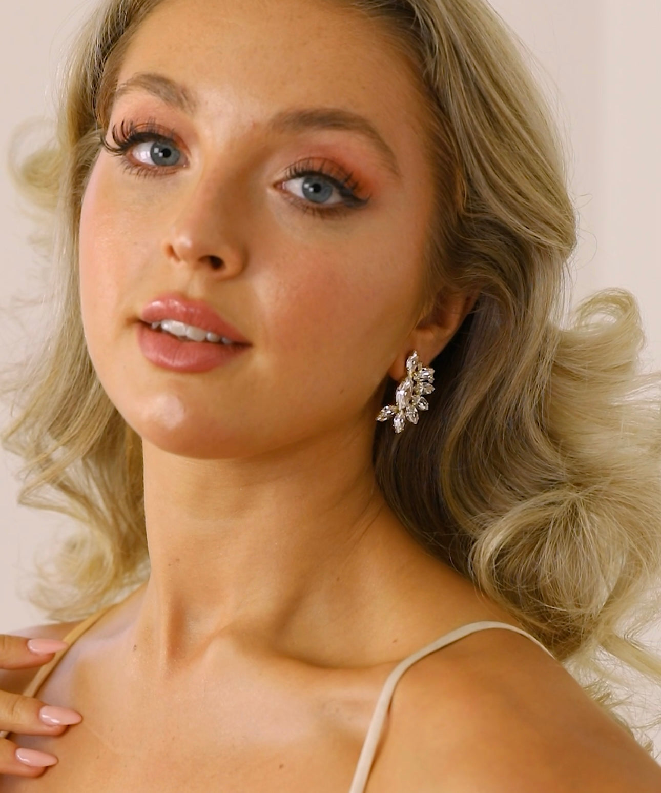 A woman wearing The Blanche Earrings, which are stud earrings with a clear crystal design.