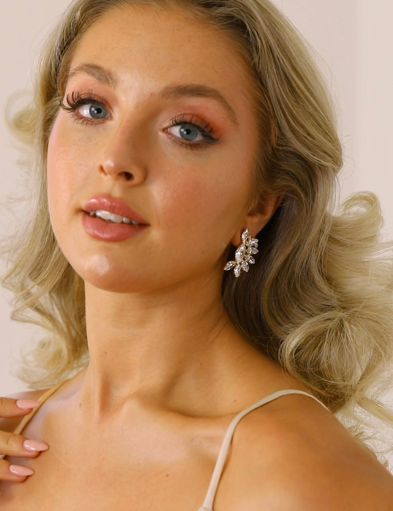 A woman wearing The Blanche Earrings, which are stud earrings with a clear crystal design.
