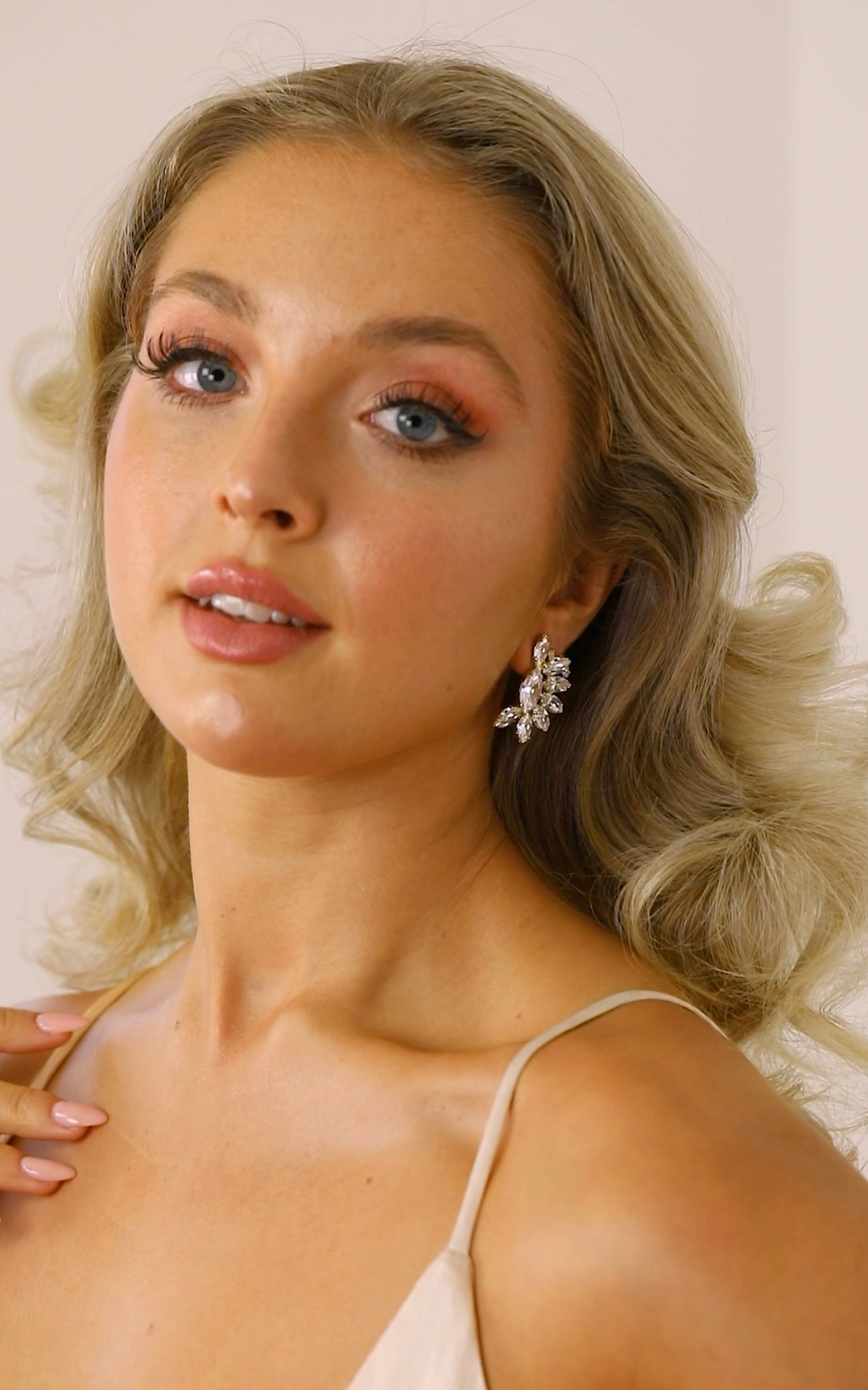 A woman wearing The Blanche Earrings, which are stud earrings with a clear crystal design.