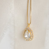 A gold-plated necklace with a teardrop-shaped pendant detailed with crystals, displayed by Sarah Gauci