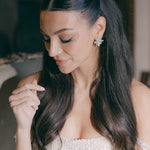 Woman with long dark hair wearing a pearl dress and sarah gauci wedding arrings.