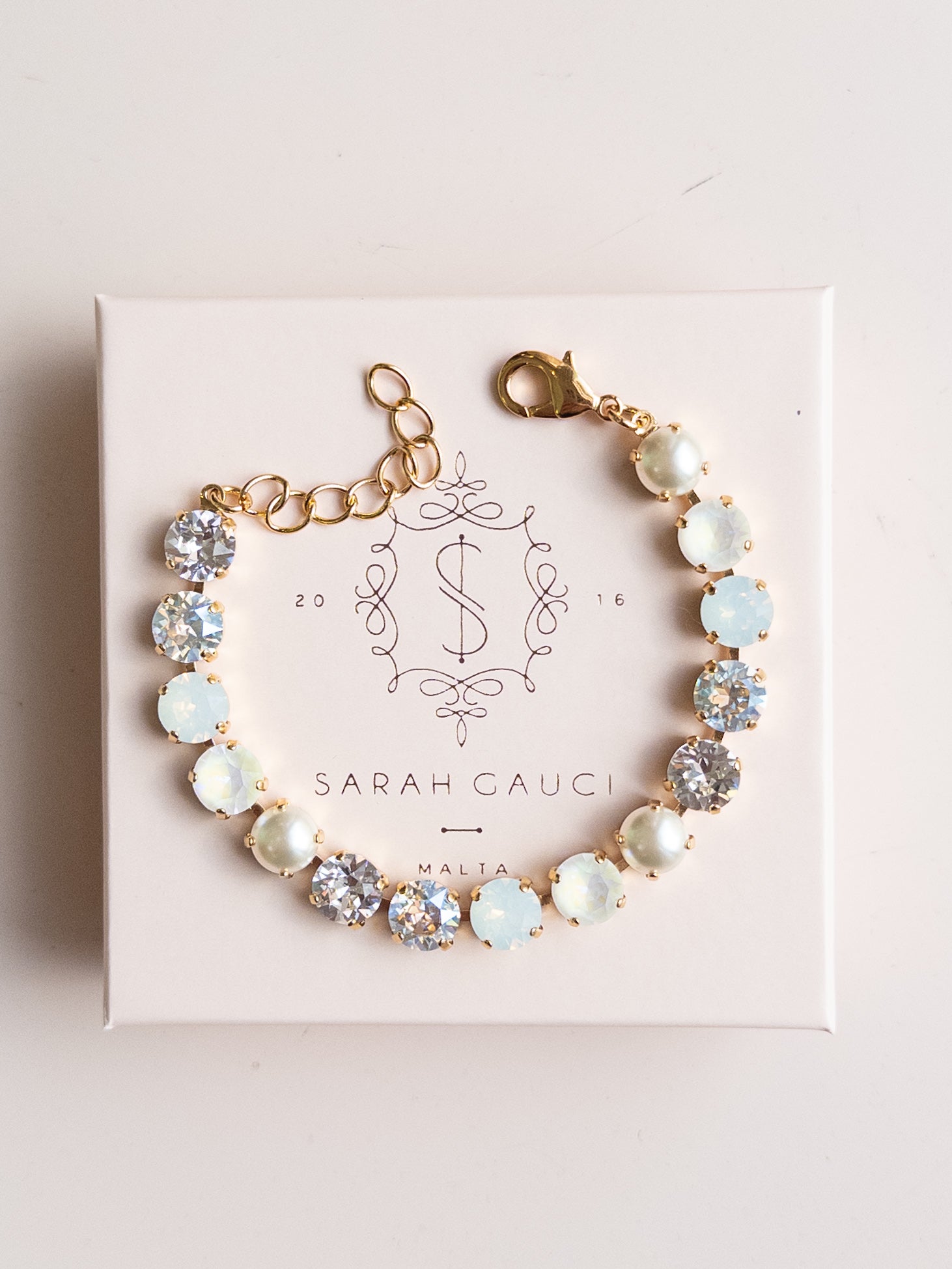 Bracelet with opal stones on a pink box with 'Sarah Gauci' branding