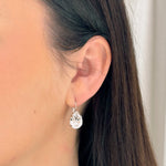 Close-up of a person wearing a teardrop-shaped earring with a blurred background